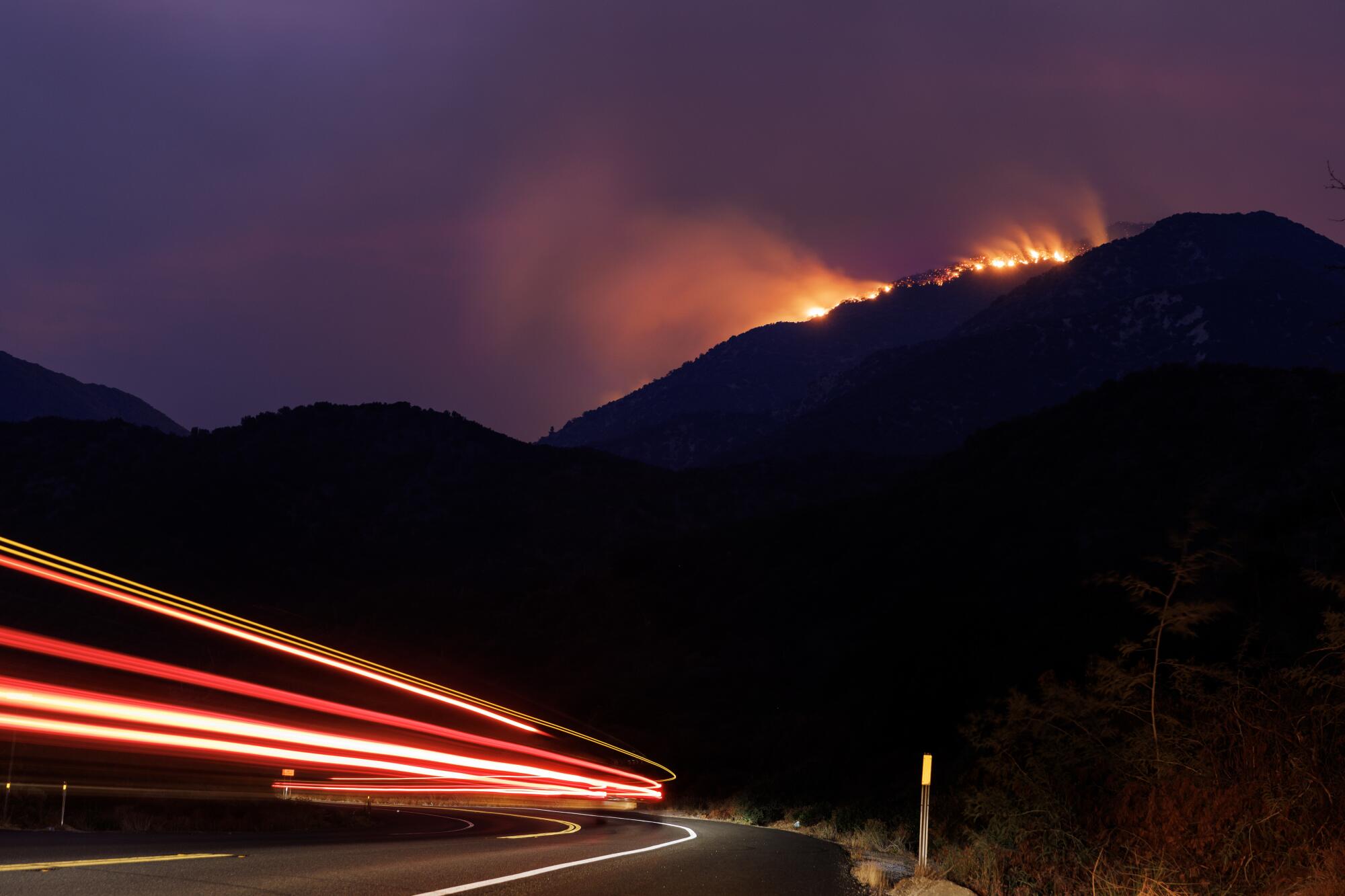 The Line fire burns on a ridge above a highway.