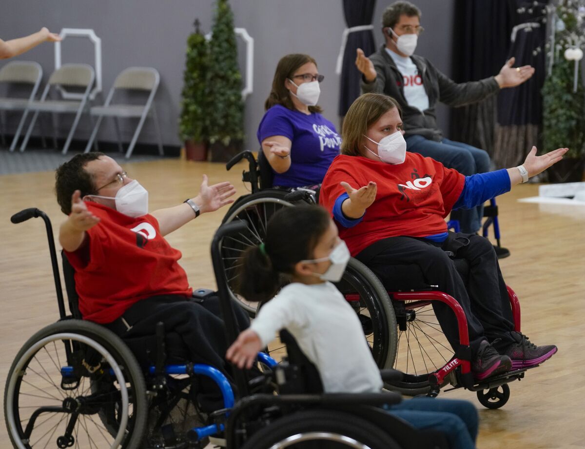 five wheelchair dancers stretch during a dance class