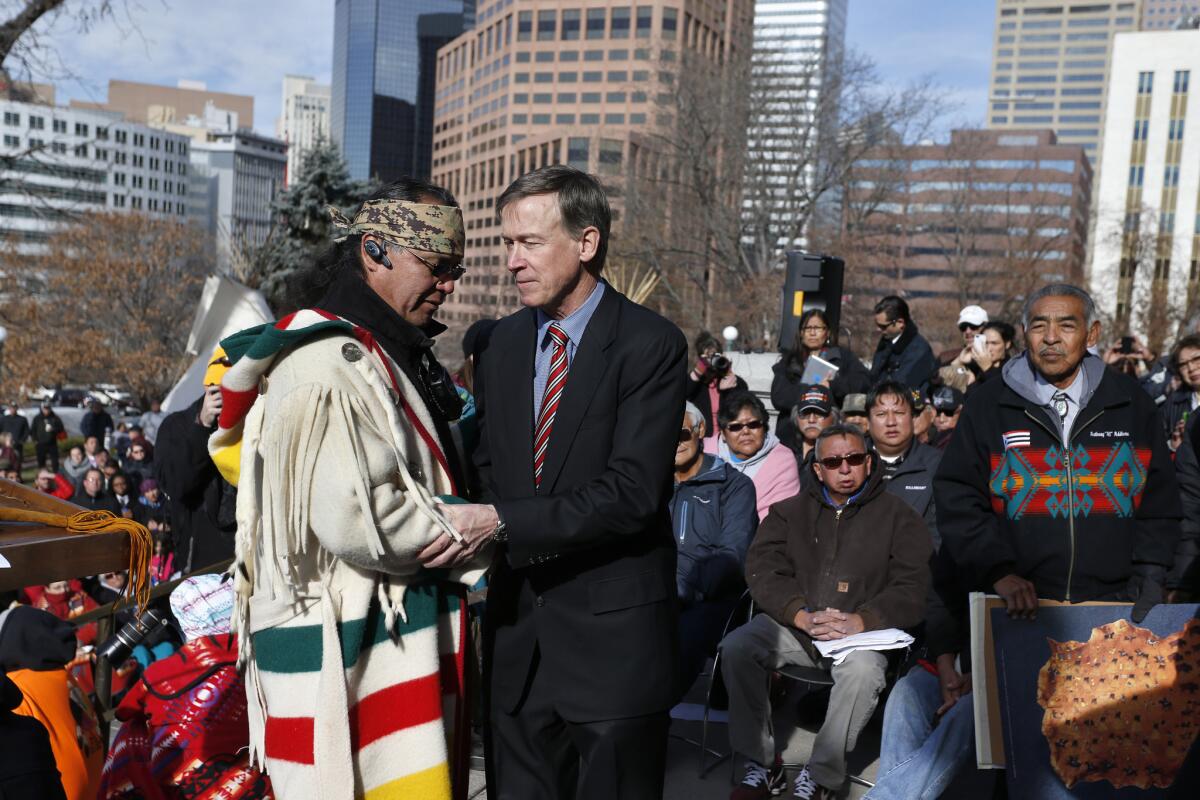 Colorado Gov. John Hickenlooper, center right, greets Northern Cheyenne tribal leader Otto Braidedhair, after speaking to members and supporters of the Arapaho and Cheyenne Native American tribes at a gathering marking the 150th anniversary of the Sand Creek Massacre.