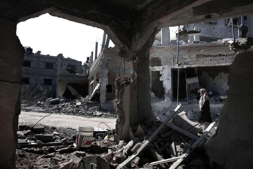 A Palestinian woman walks past destroyed buildings in the northern Gaza Strip city of Beit Hanun.