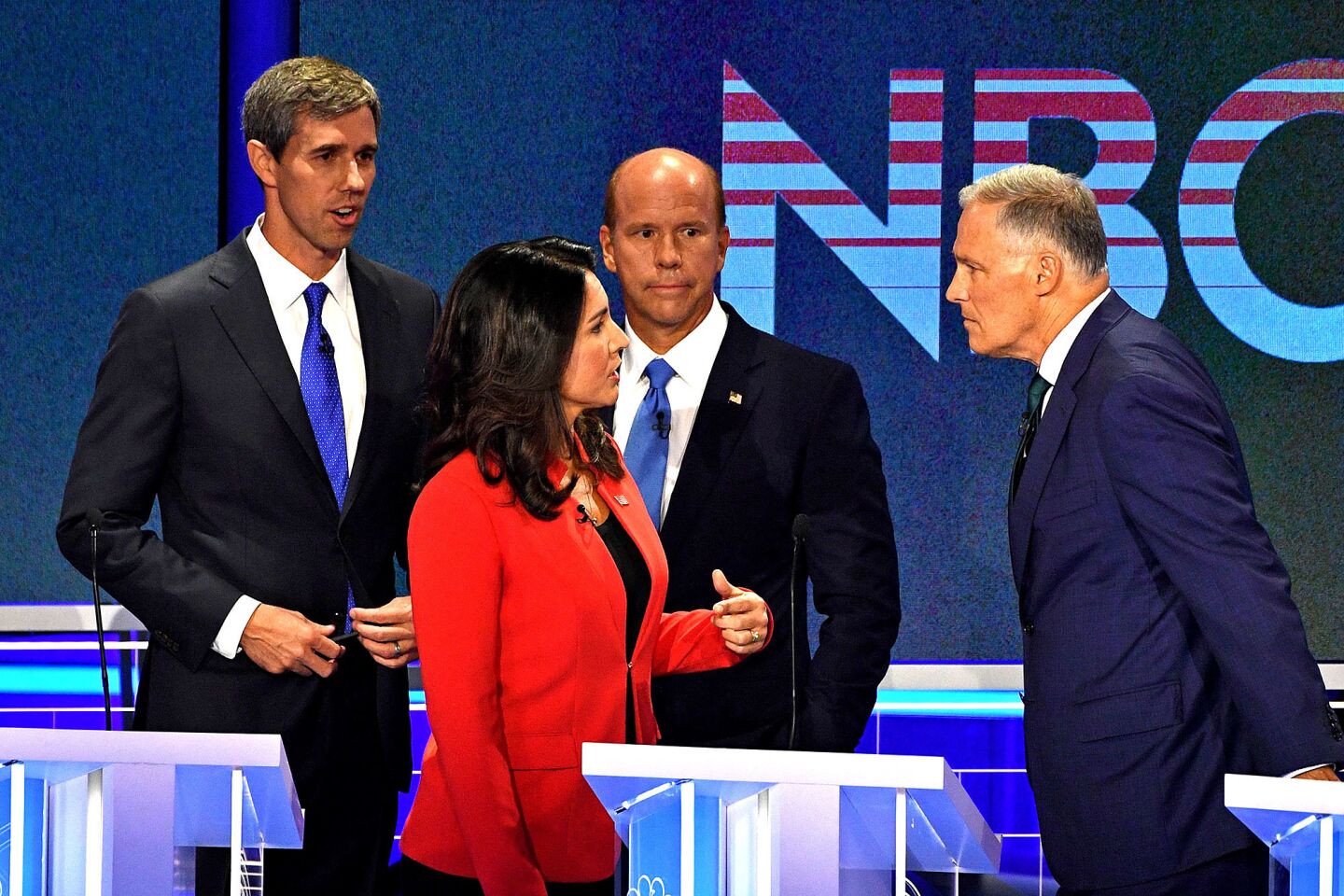Democratic presidential hopeful US Representative for Hawaii's 2nd congressional district Tulsi Gabbard (C) speak to Governor of Washington Jay Inslee (R), former US Representative for Maryland's 6th congressional district John Delaney and former US Representative for Texas' 16th congressional district Beto O'Rourke during a brake of the first Democratic primary debate of the 2020 presidential campaign season hosted by NBC News at the Adrienne Arsht Center for the Performing Arts in Miami, Florida, June 26, 2019.