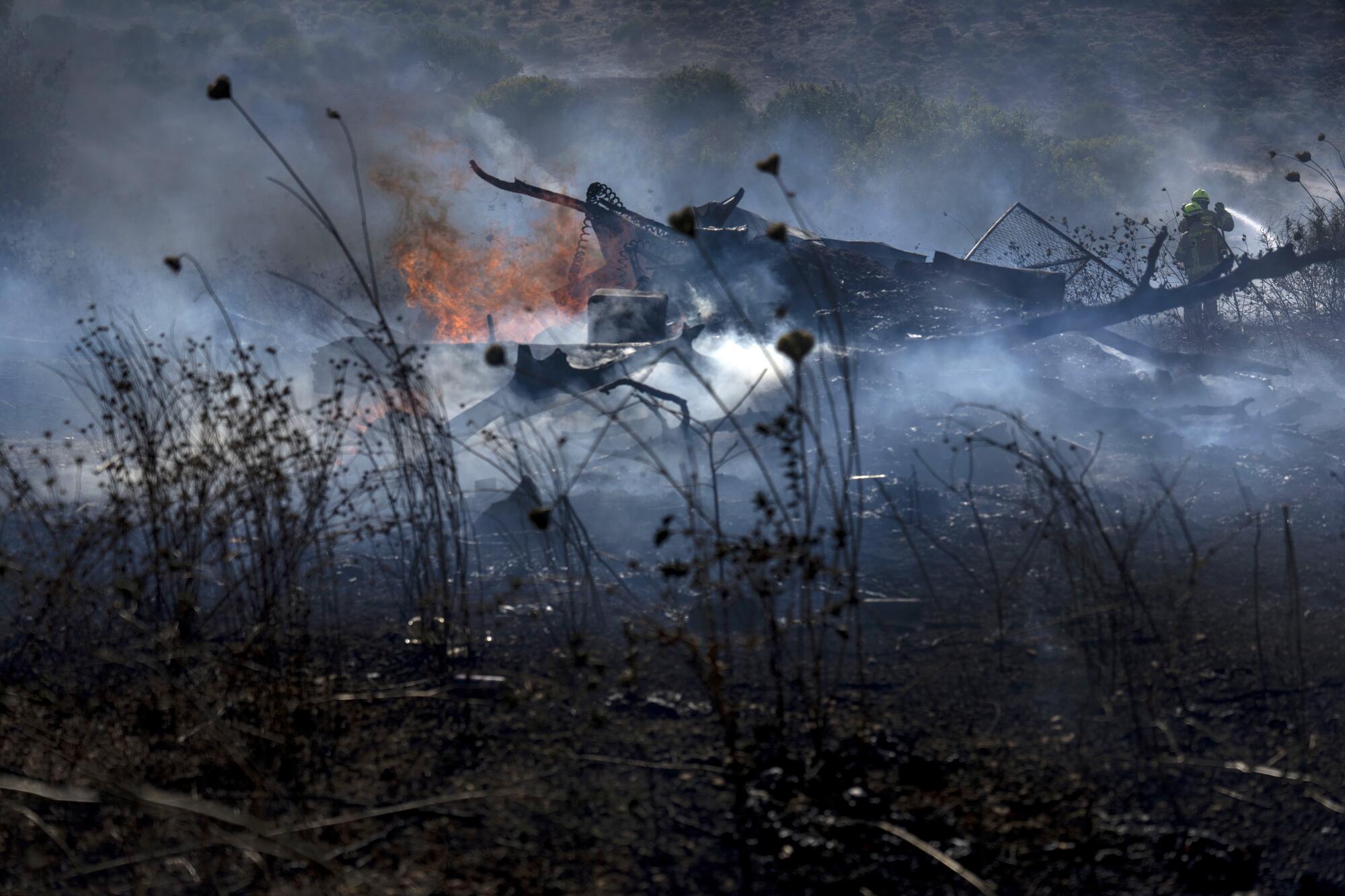 Israeli firefighters extinguish a fire burning amid grasses. 