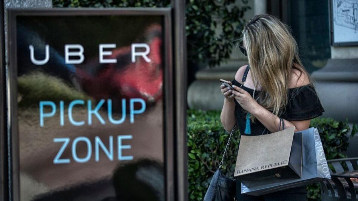 A shopper at the Grove waits for a ride in a designated Uber pickup zone.