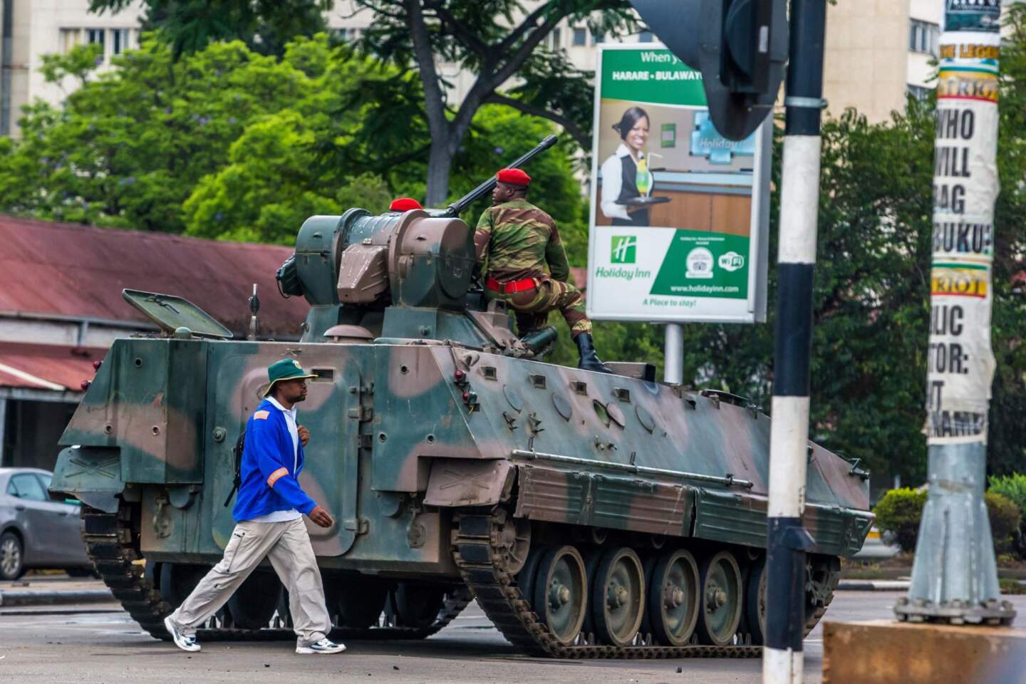 A man walks past an armored personnel carrier as Zimbabwean soldiers regulate traffic in Harare. Zimbabwe's military appeared to be in control of the country as generals denied staging a coup but used state television to vow to target "criminals" close to President Mugabe.