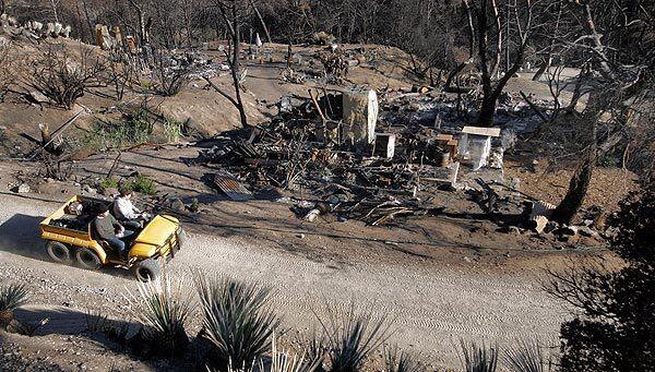 A film crew passes destroyed buildings at Singing Springs in the Angeles National Forest, which was used for movie shoots and music videos until Aug. 20, when the Station fire swept across the family retreat-turned-movie-ranch. The fire wiped out all 11 buildings on the 16 1/2-acre site along Angeles Forest Highway, destroying props, tools, keepsakes and furnishings.