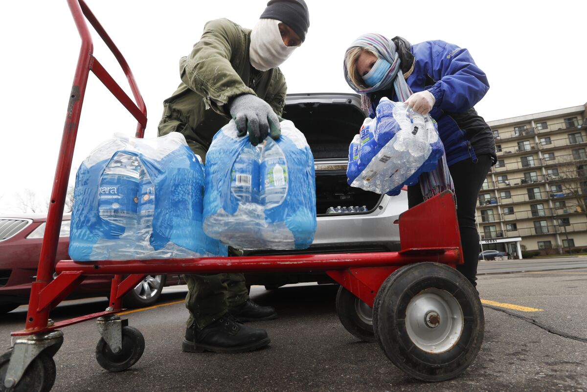 At the Brightmoor Connection Food Pantry in Detroit, Rabbi Yosef Chesed, left, helps unload bottled water being donated by Lorie Lutz, right, on March 23, 2020, to help families whose water had been cut off during the COVID-19 pandemic.