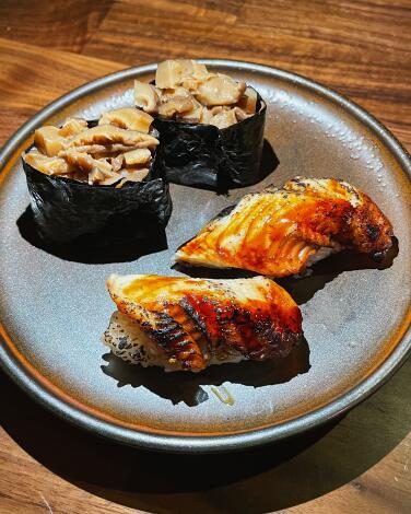 Two pieces of unagi nigiri on a stoneware plate with two gunkan filled with sautéed mushrooms at Santo in Silver Lake