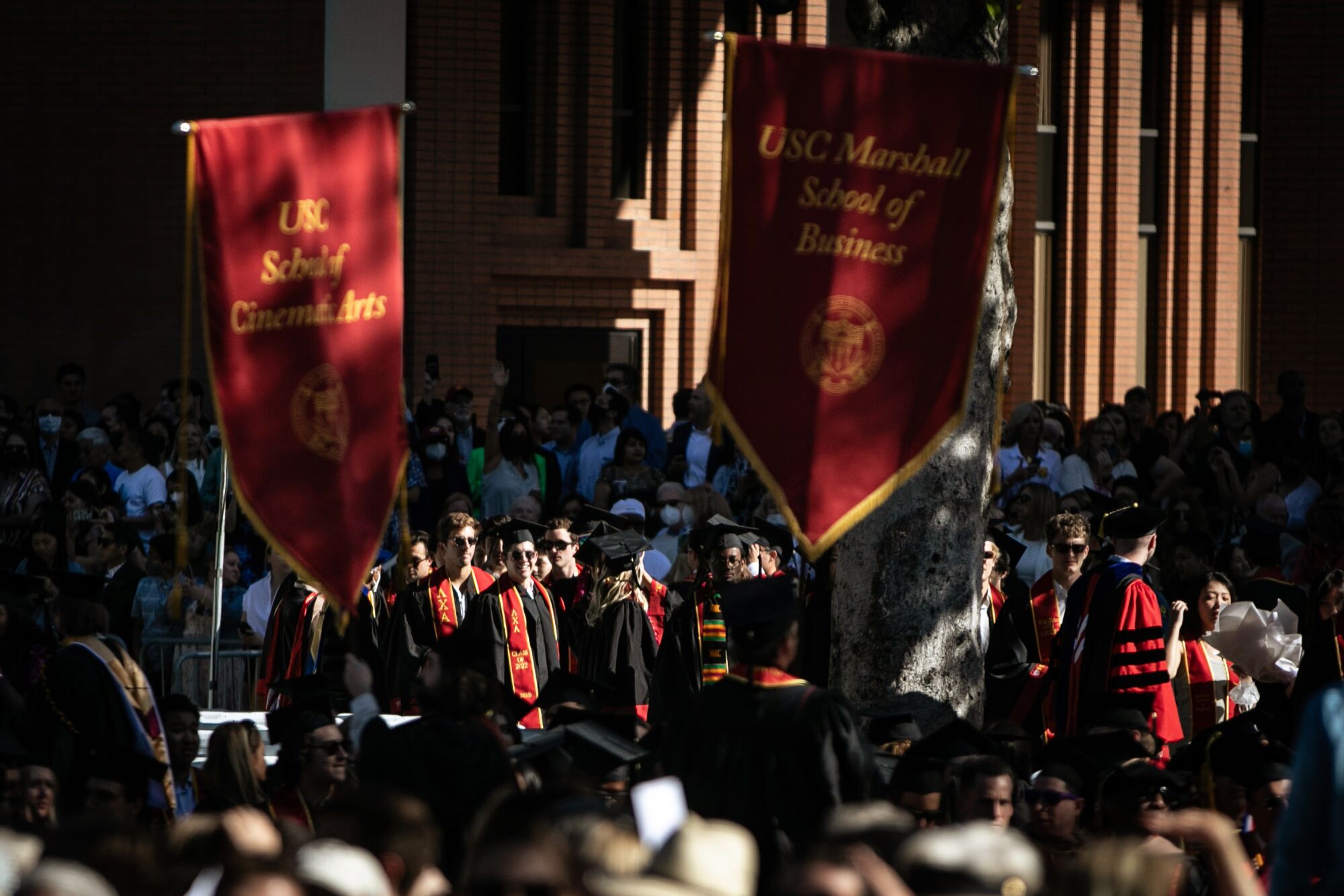 Graduates gather under banners for USC School of Cinema Arts and USC Marshall School of Business.