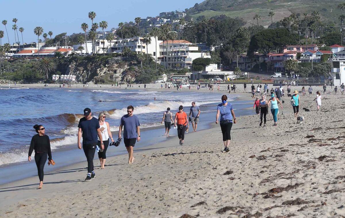 People walk the sands between Cleo Street Beach and Main Beach as Laguna Beach opens its city beaches on Tuesday for weekday active use only between the hours of 6 a.m. and 10 a.m.