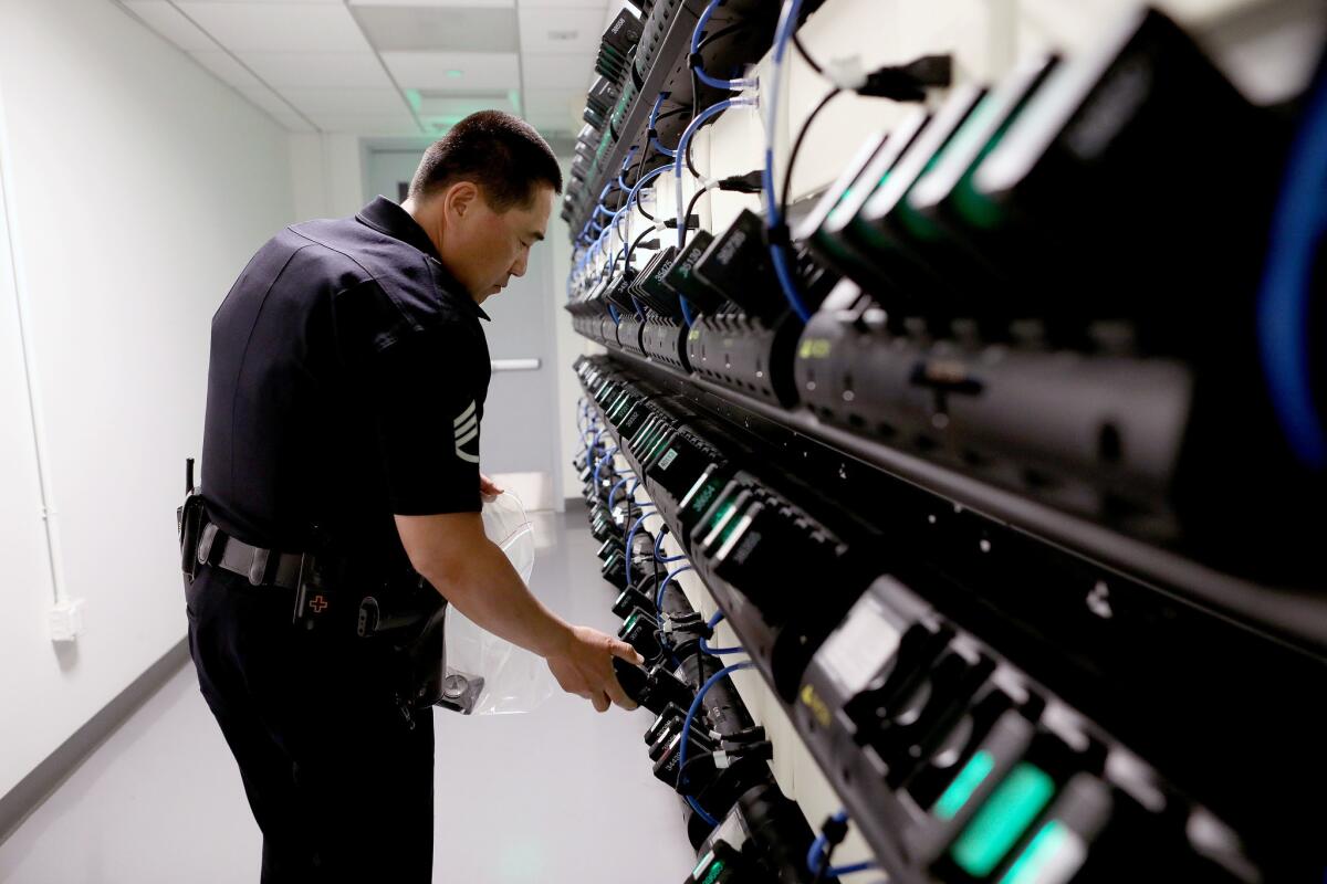 LAPD Metropolitan Division Sgt. Steve Hwang inserts body cameras into docking stations to download footage from that night's encounters.