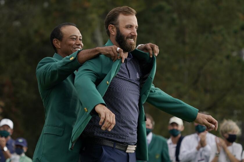 Tiger Woods helps Masters' champion Dustin Johnson with his green jacket after his victory at the Masters golf tournament.
