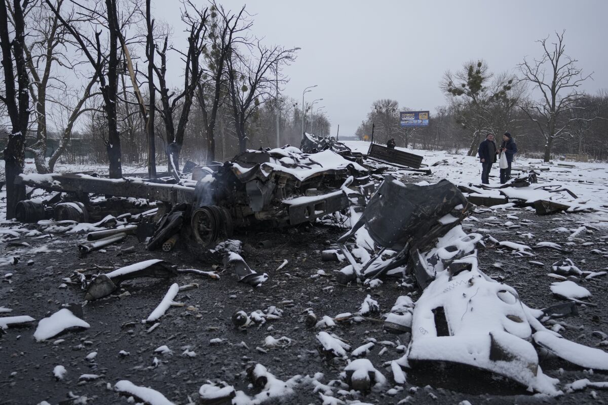 People walk by smoldering Russian military vehicles