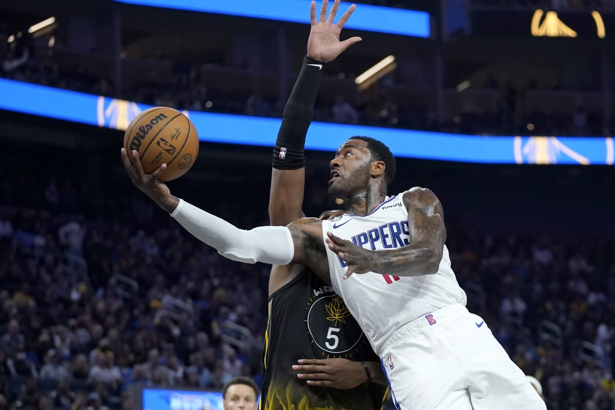 Clippers guard John Wall extends the ball to the basket as he attempts a layup against Warriors center Kevon Looney.