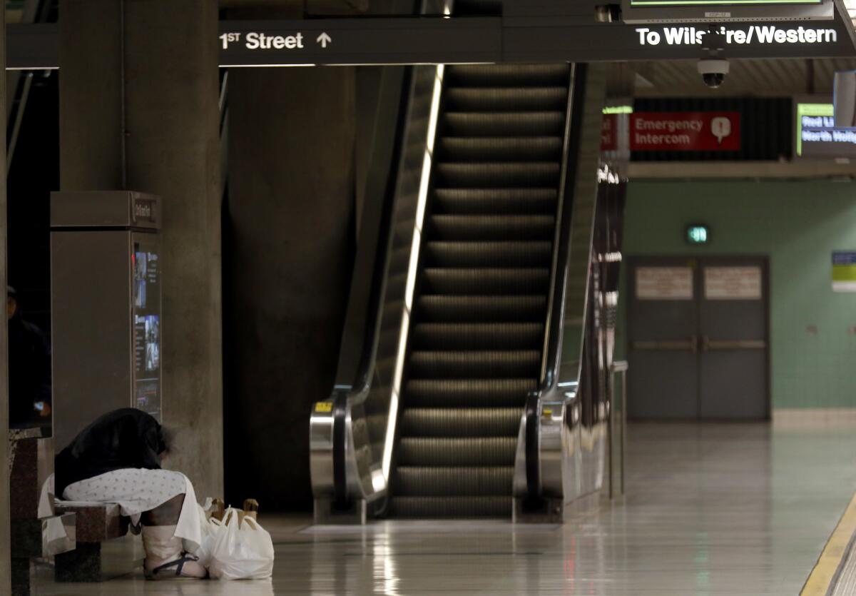 With swollen legs and wearing a hospital gown early in the morning, a homeless man sits on bench at the Civic Center metro station in Los Angeles.