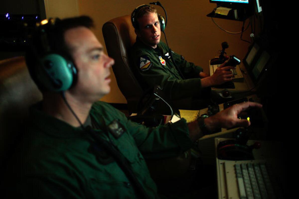 U.S. Air Force Capt. Sam Nelson, on the left console, looks to his sensor operator while the team flies its drone on a mission over Afghanistan. The two men operate from Creech Air Force Base in Nevada as part of the 432d Air Expeditionary Wing.
