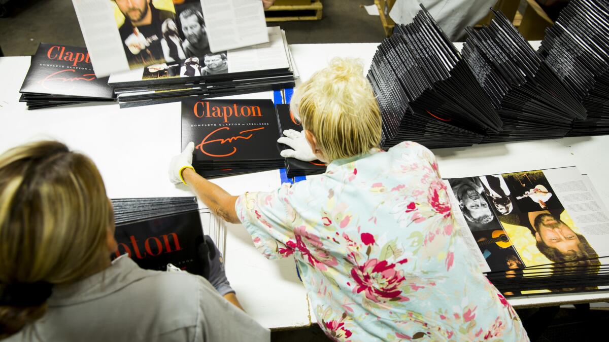 Workers prepare Eric Clapton vinyl album jackets for shipping at Stoughton Printing in 2014. Stoughton offers health insurance through a plan in which small businesses jointly purchase coverage.
