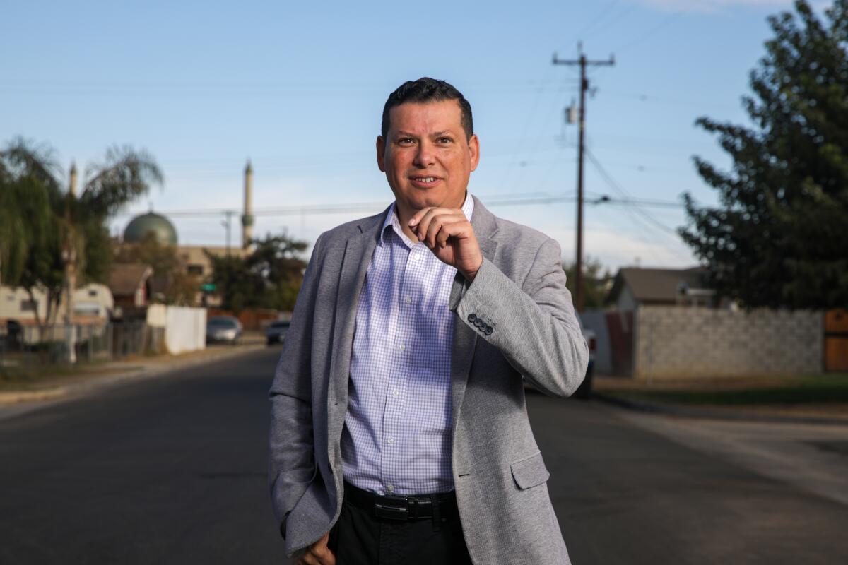Rudy Salas standing in a residential street, raising a hand toward his chin