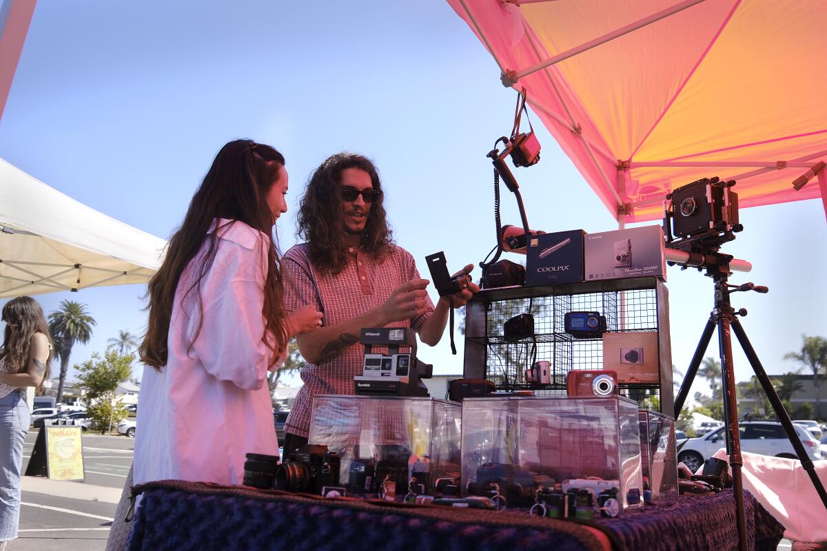 Sophy Samonte watches Patrick Doherty, owner of Film47, as he shows film loading in a camera at LeucadiART Walk.