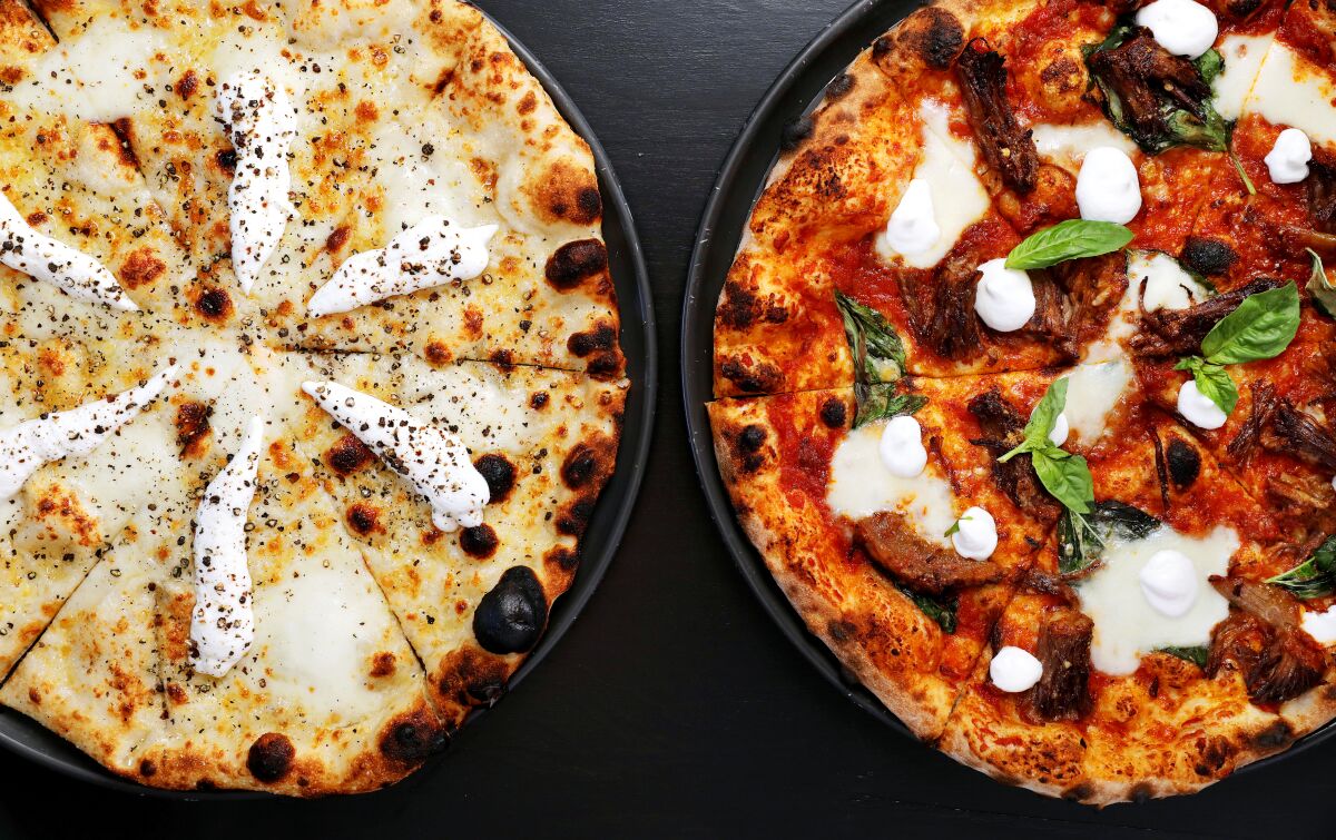 An overhead photo of two Pizzana pizzas on a black tabletop.