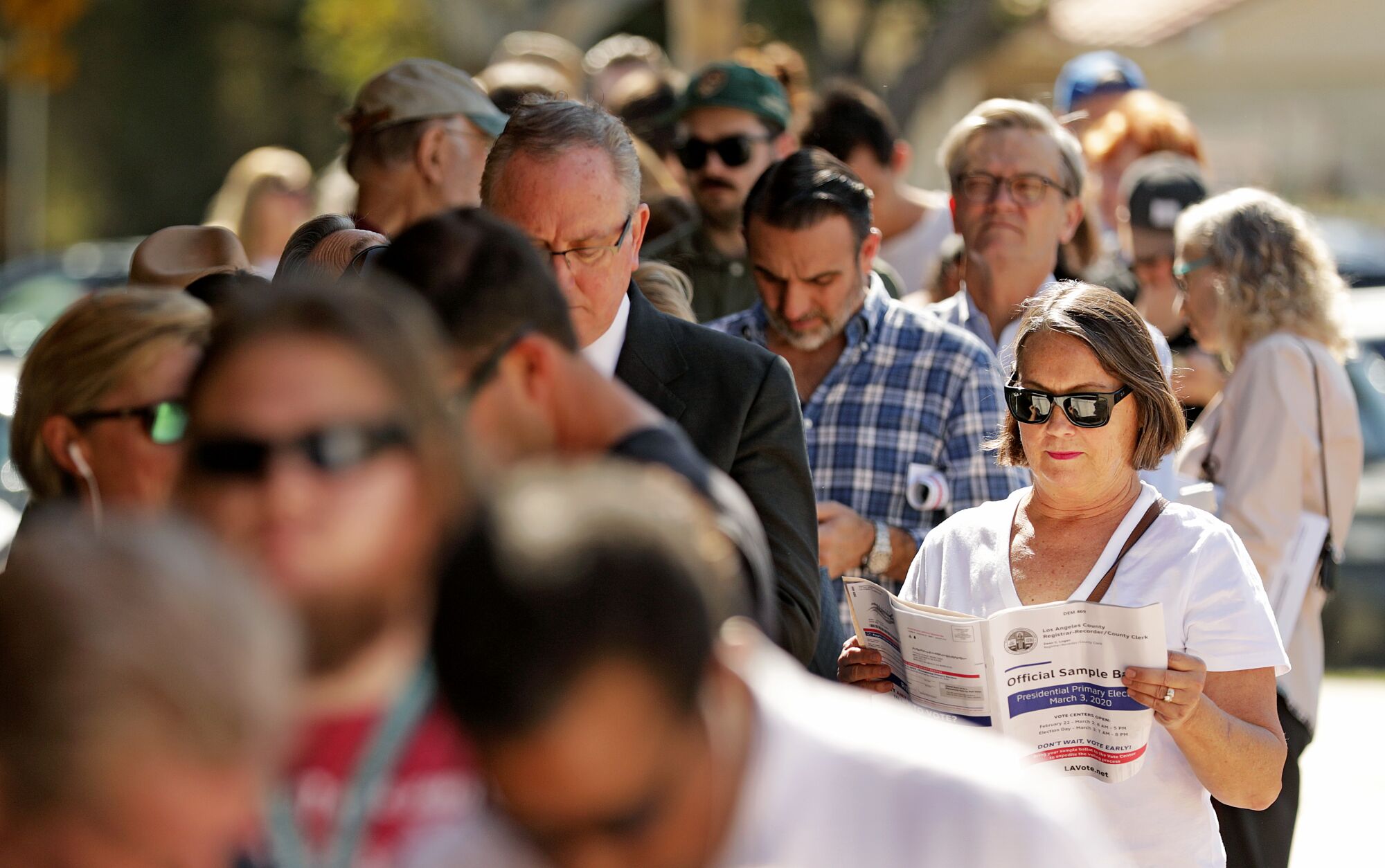 A crowd of voters stand outside in a line, some in sunglasses, on March 3. 