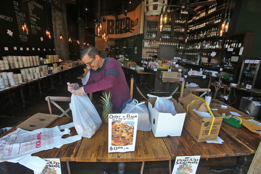 Bacari Assistant General Manager Eduardo Aponte prepares online orders at the Bacari GDL Pop-Up Market at the Americana at Brand in Glendale on Monday, March 30, 2020. Bacari, which normally serves tapas, beverages and pizza, has pivoted into a local market with grains, produce, wines, and $13 pizza.
