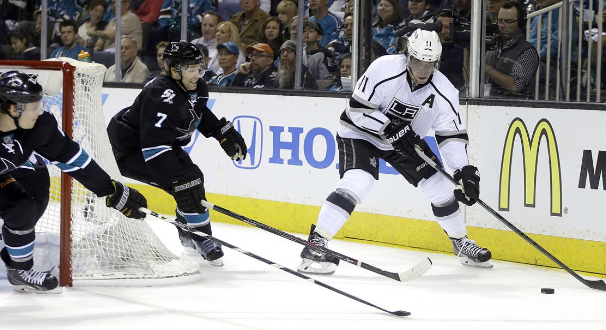 Kings center Anze Kopitar (11) maneuvers behind the net as Sharks defenseman Brad Stuart (7) pursues the play during the first period of Game 1 on Thursday, in San Jose.
