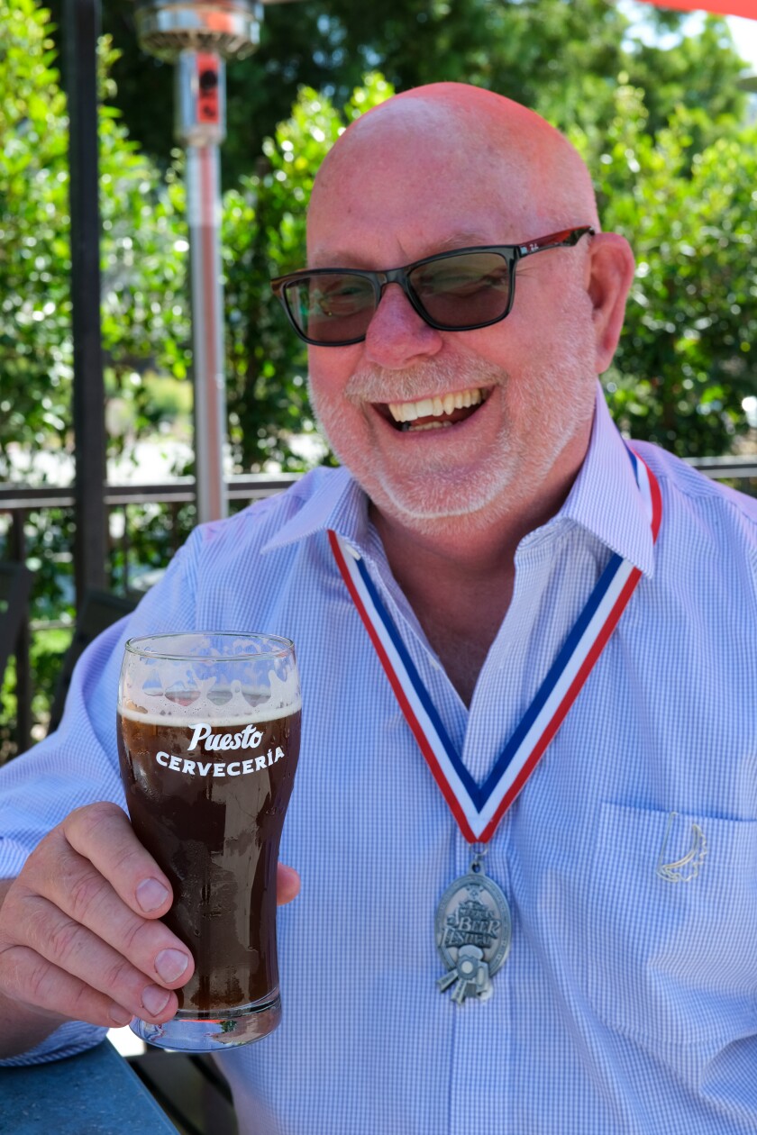 Puesto's head brewer, Doug Hasker, holds his award-winning dark beer Puesta Negra.
