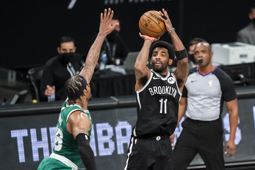 Brooklyn Nets guard Kyrie Irving is defended by Boston Celtics guard Marcus Smart during a basketball game.