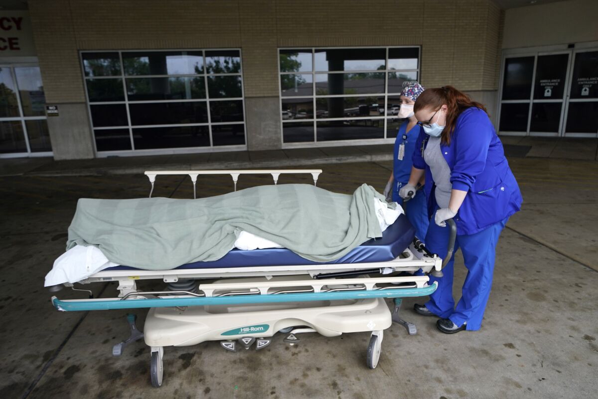 Medical staff prepare to move the body of a COVID-19 patient to a funeral home van in Shreveport, La.