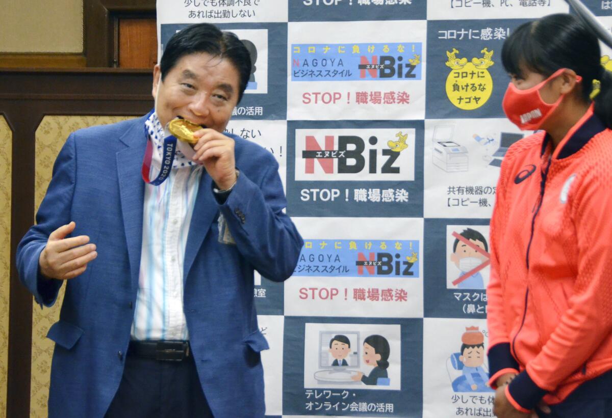 El alcalde de Nagoya, Takashi Kawamura, izquierda, muerde la presea de oro