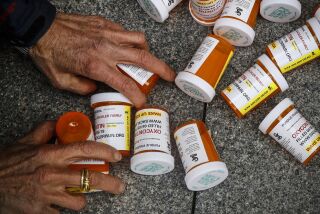FILE - A protester gathers containers that look like OxyContin bottles at an anti-opioid demonstration in front of the U.S. Department of Health and Human Services headquarters in Washington, on April 5, 2019. A judge has kept lawsuits against OxyContin maker Purdue Pharma and members of the Sackler family who own it on hold until Feb. 1, 2022, but ordered the parties involved to negotiate a new settlement. (AP Photo/Patrick Semansky, File)