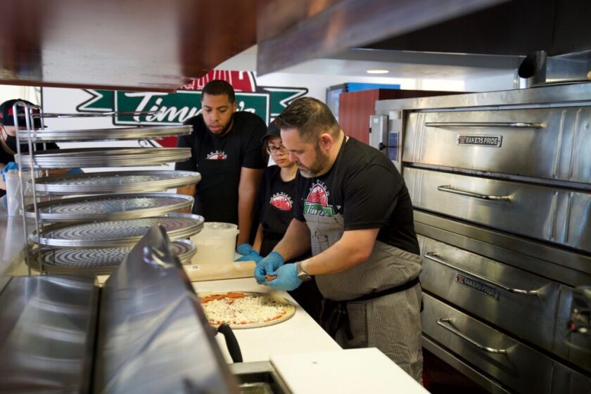 Workers at Timmy's Place add toppings to a pizza on opening day. 
