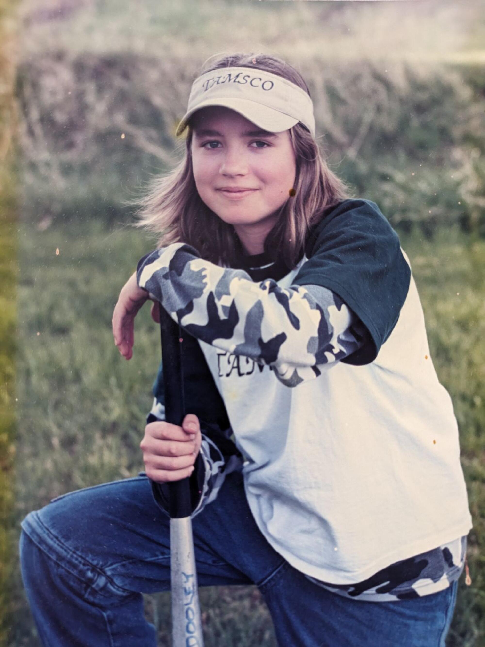 A girl wearing a visor in a grassy field 