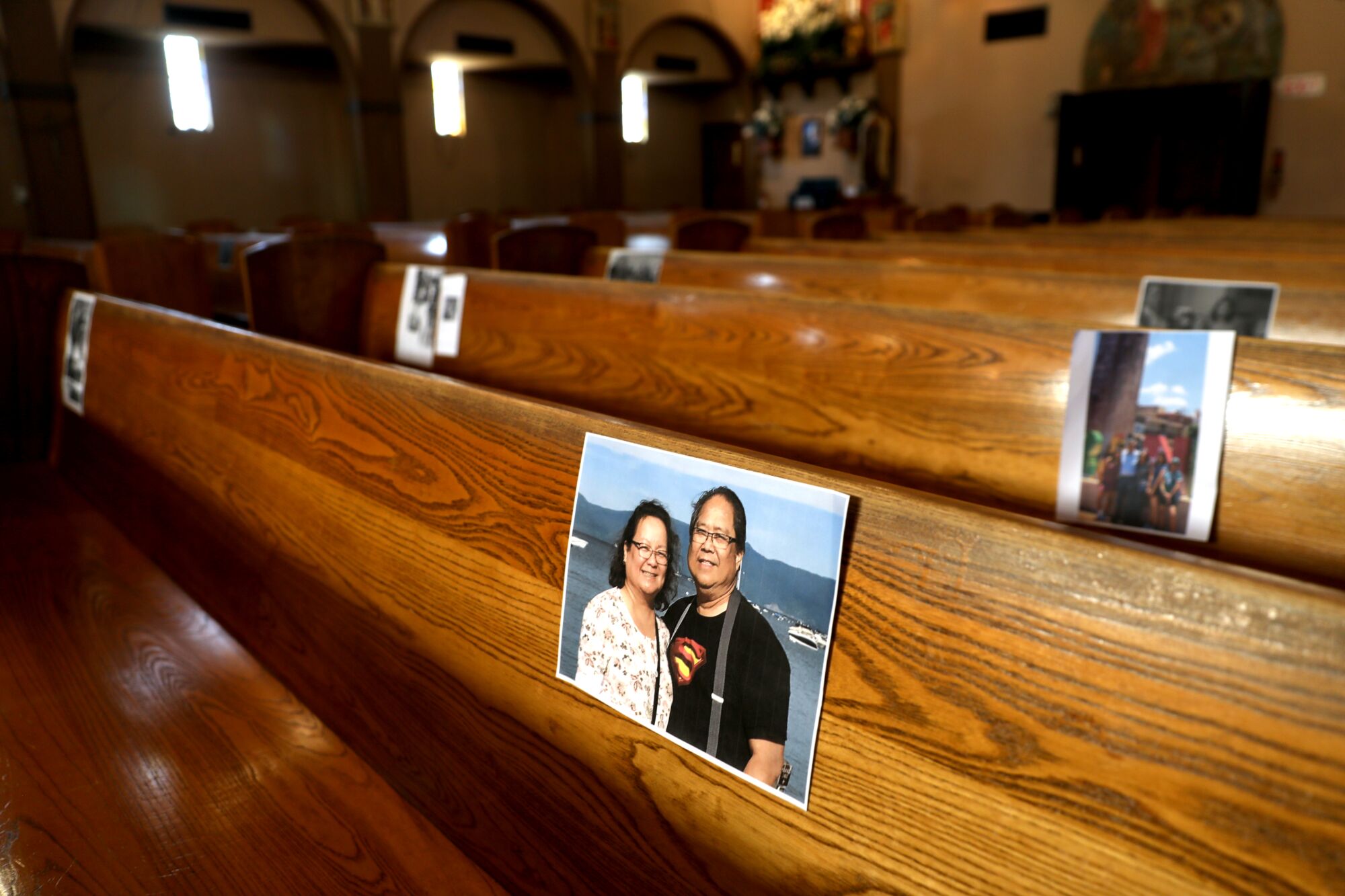 Photos of parishioners, including Henry and Gloria Lucio, are placed in the pews in preparation for Easter service at Holy Trinity Catholic Church.