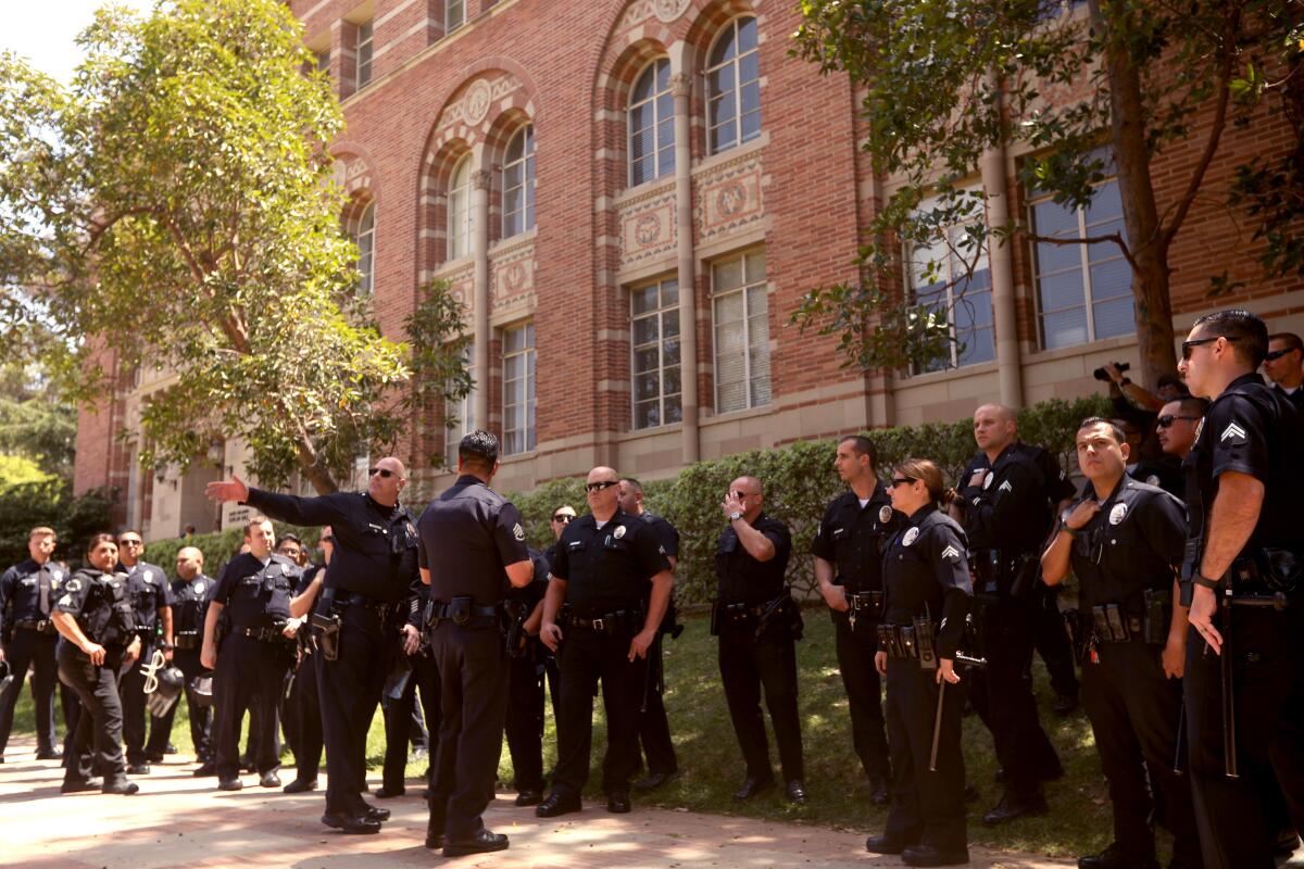 Campus police officers confer outside a UCLA building.