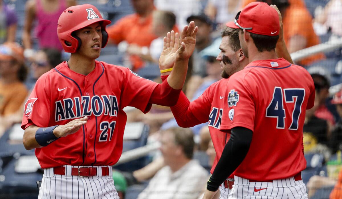 Arizona's Ryan Aguilar, left, celebrates with teammates after scoring on a sacrifice fly by Jared Oliva during the first inning of a College World Series baseball game against Oklahoma State on Saturday.