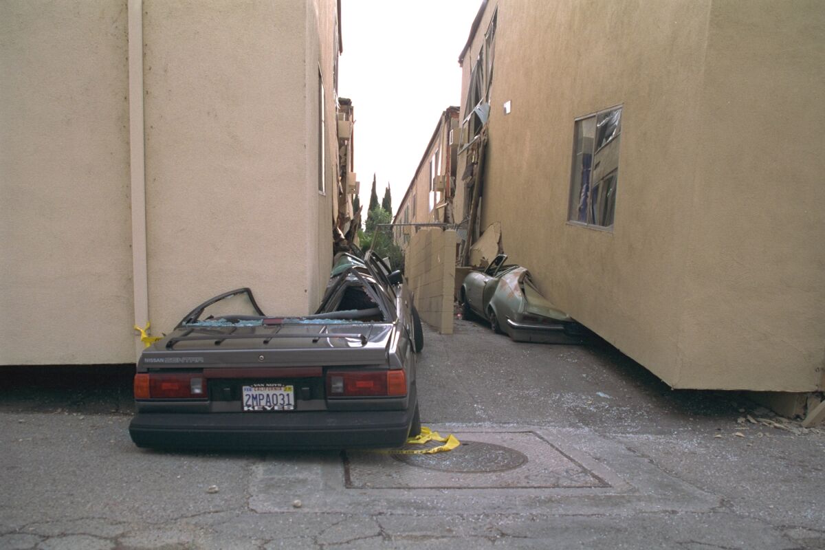 Cars are crush flat beneath two apartment buildings