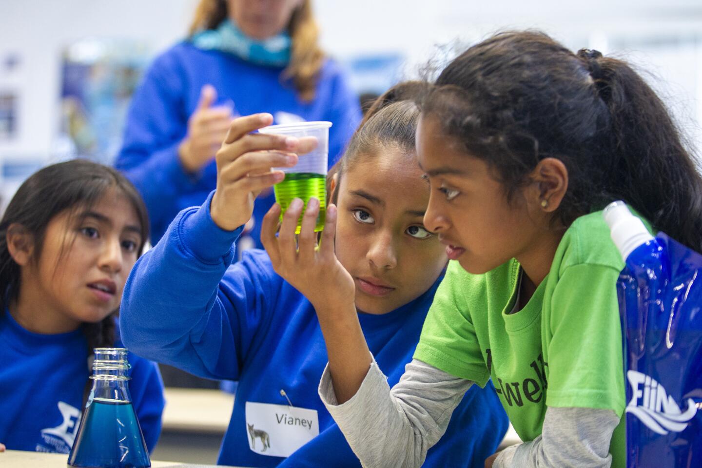 Valeria Pedraza, 11, left, Vianey Olivier, 10, and Kiara Padilla, 10, watch a beaker for a reaction after mixing salt water and fresh water during the FiiN (Fostering interest in Nature) program at the Back Bay Science Center in Newport Beach on Tuesday.
