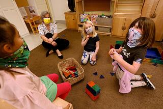 SANTA MONICA, CA - FEBRUARY 23, 2021 - - Elke Miller, second from left, executive director at Kigala Preschool, watches over kindergarten students Laila, from left, Ray and Emmy Lou, all 6, who attend class at the Kigala Preschool in Santa Monica on February 23, 2021. The school has been admitting students from kindergarten through 1st grade. With most K-12 schools still closed across California, preschools and daycares have adopted older children into their programs. Often, up to a third of children in these facilities are learning remotely from shuttered public schools. But preschool and daycare providers make far less than their K-12 counterparts, and are far more likely to be women of color. The added complexity and expense of caring for older children has strained an already struggling system. (Genaro Molina / Los Angeles Times) ATTENTION EDITOR: DIRECTOR OF SCHOOL ONLY WANTED FIRST NAME OF STUDENTS USED.