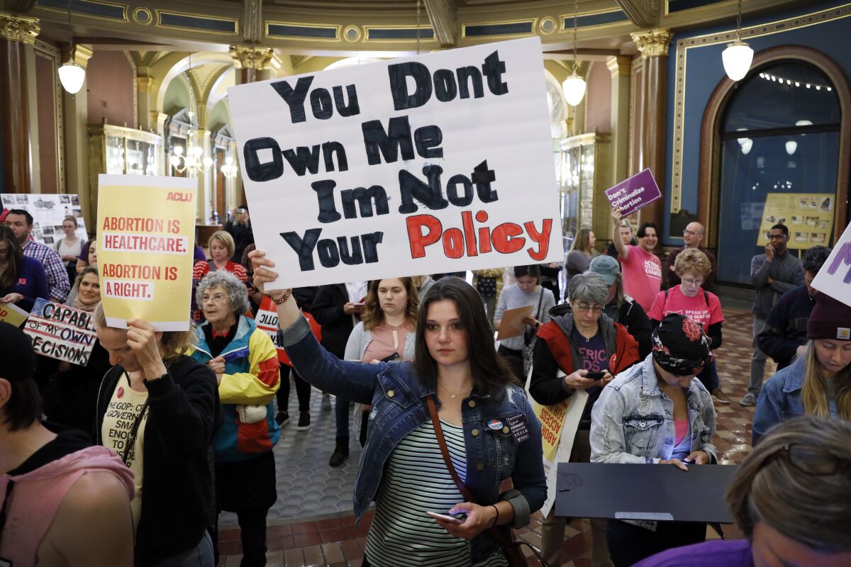 FILE - Marissa Messinger, of Lake View, Iowa, center, holds a sign during a rally to protest recent abortion bans, May 21, 2019, at the Statehouse in Des Moines, Iowa. The Iowa Supreme Court on Friday, June 17, 2022, cleared the way for lawmakers to severely limit or even ban abortion in the state, reversing a decision by the court just four years ago that guaranteed the right to the procedure under the Iowa Constitution. (AP Photo/Charlie Neibergall, File)