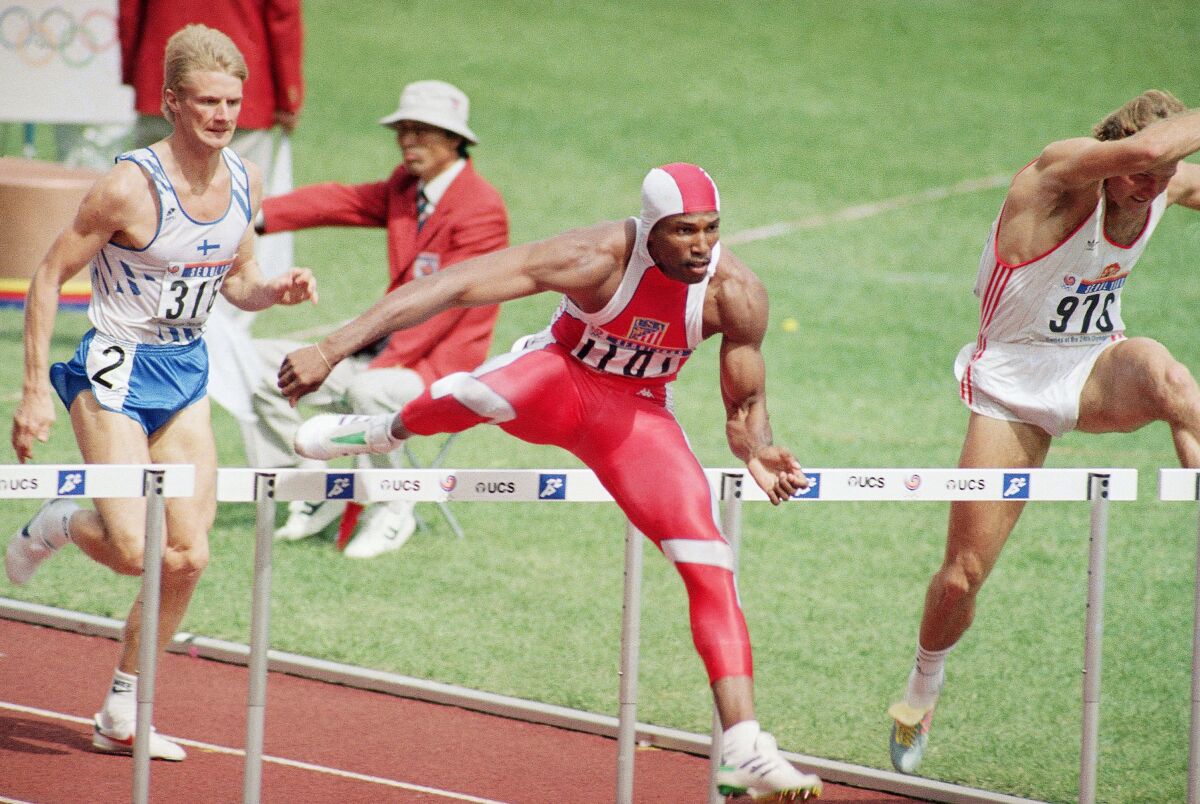 Roger Kingdom clears a hurdle in the men's 110-meter hurdles semifinal with competitors nearby.