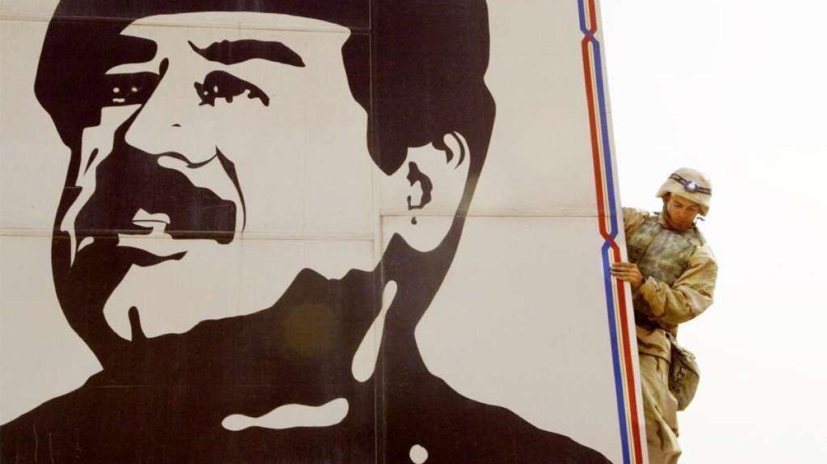 A U.S. Marine pulls down a billboard of Saddam Hussein in Safwan, Iraq, on March 23, 2003.