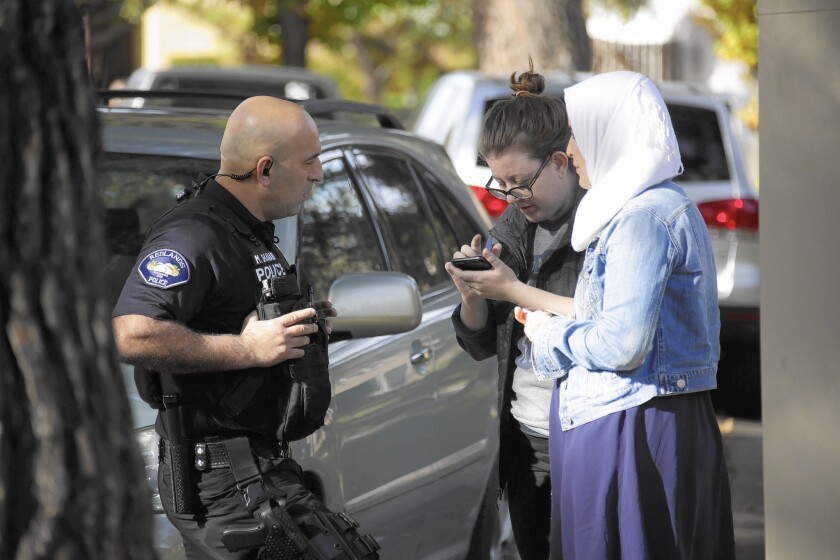 A Redlands police officer takes a statement Thursday from Rhian Beutler, center, and an unidentified woman at right after the woman was repeatedly harassed by a passing motorist.