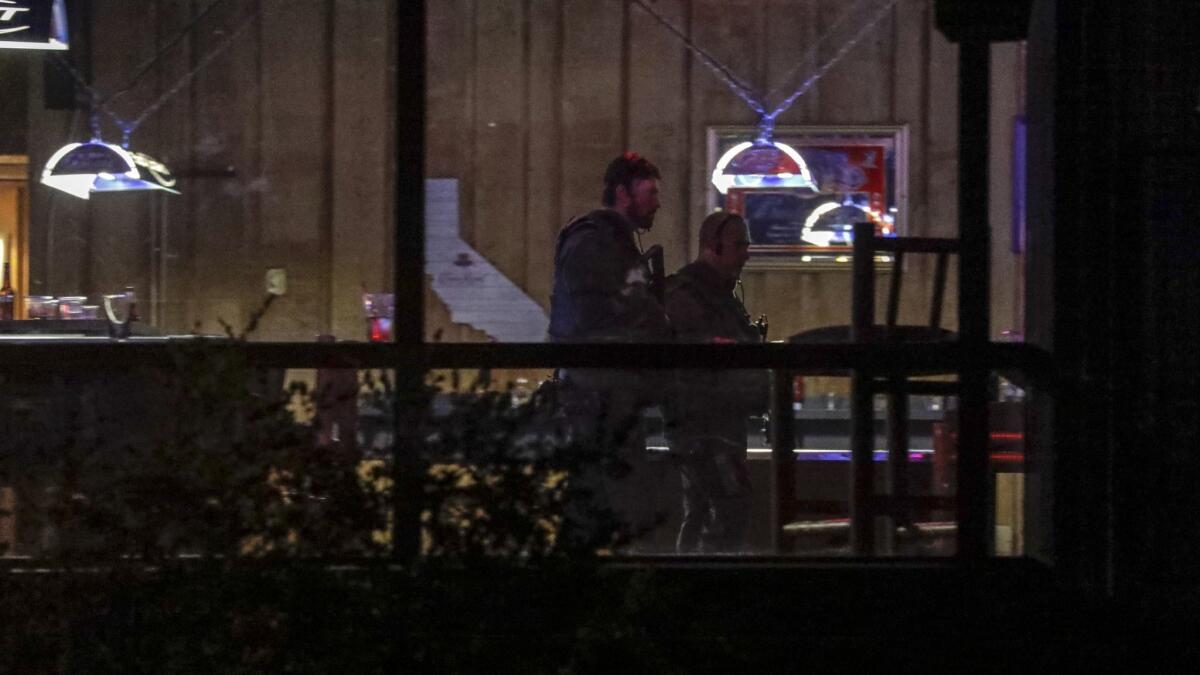 Law enforcement officers scour the scene of Wednesday night's mass shooting at a Thousand Oaks bar and grill where a lone gunman killed 12 people, including a Ventura County sheriff's sergeant whose decision to quickly confront him was credited with saving more lives.