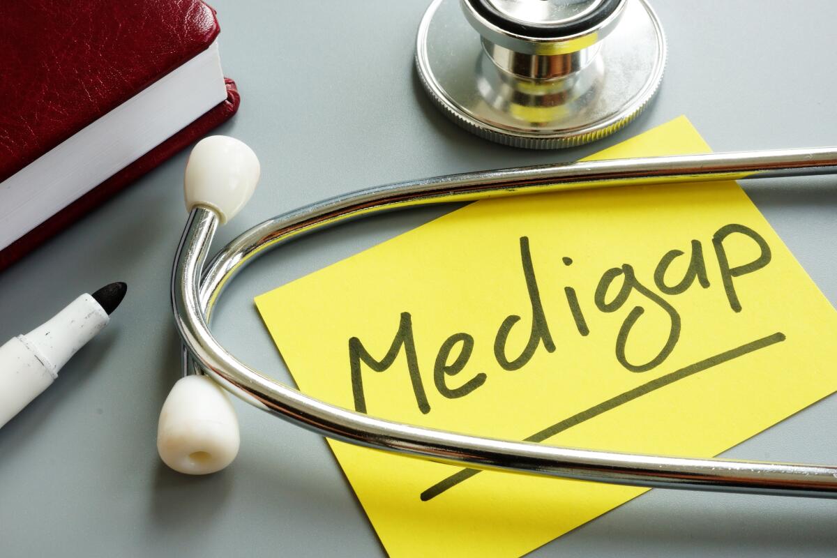 This photo shows a piece of paper with the word Medigap on it. A stethoscope lies over the note.