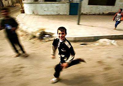 An Iraqi boy runs alongside a bus filled with foreign journalists Friday morning as it tours the city following a night of bombing.