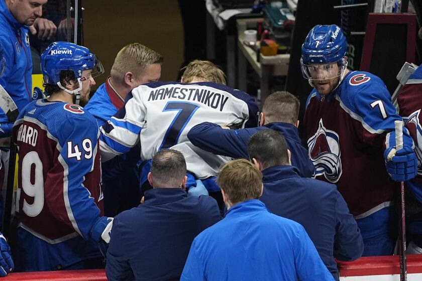Winnipeg Jets center Vladislav Namestnikov, center, is helped off the ice after taking a slap shot in the face in the third period of Game 4 of an NHL Stanley Cup first-round playoff series against the Colorado Avalanche, Sunday, April 28, 2024, in Denver. (AP Photo/David Zalubowski)
