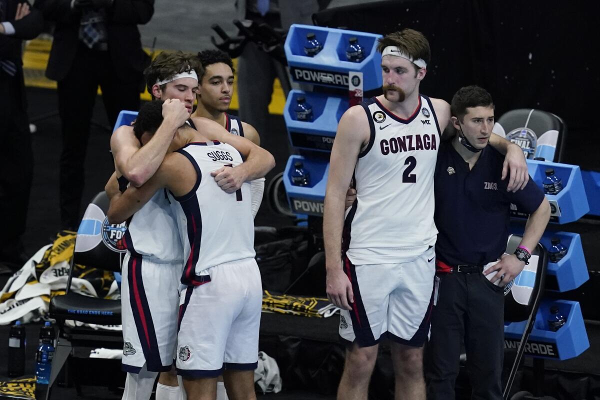 Gonzaga forward Corey Kispert hugs Jalen Suggs as forward Drew Timme looks on.