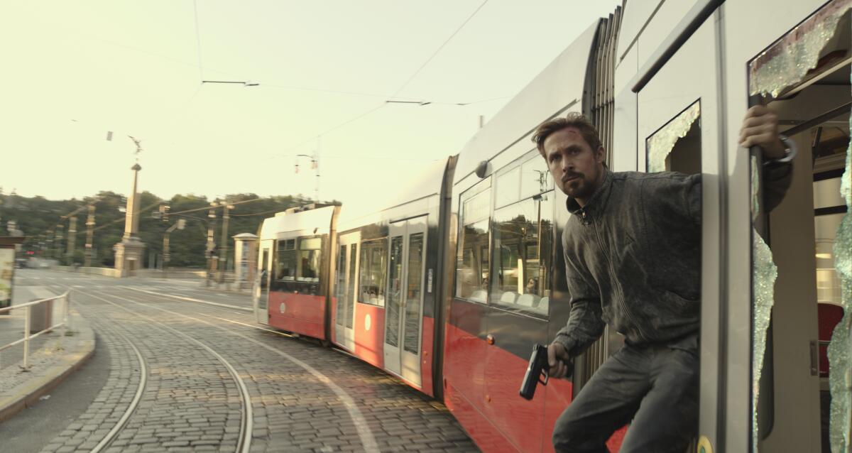 A man hangs out a train door holding a gun
