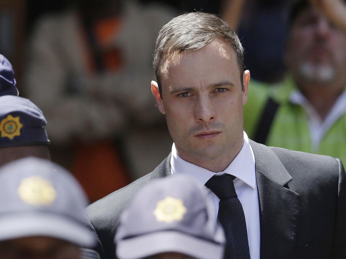 Oscar Pistorius is escorted by police officers as he leaves the high court in Pretoria, South Africa, on Oct. 17.
